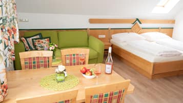 Ein gemütliches Zimmer mit einem Holzespeisetisch, einem grünen Sofa und einem Einzelbett.