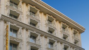 Un hotel de varios pisos con estilo arquitectónico clásico, que cuenta con balcones y un letrero de hotel llamativo.