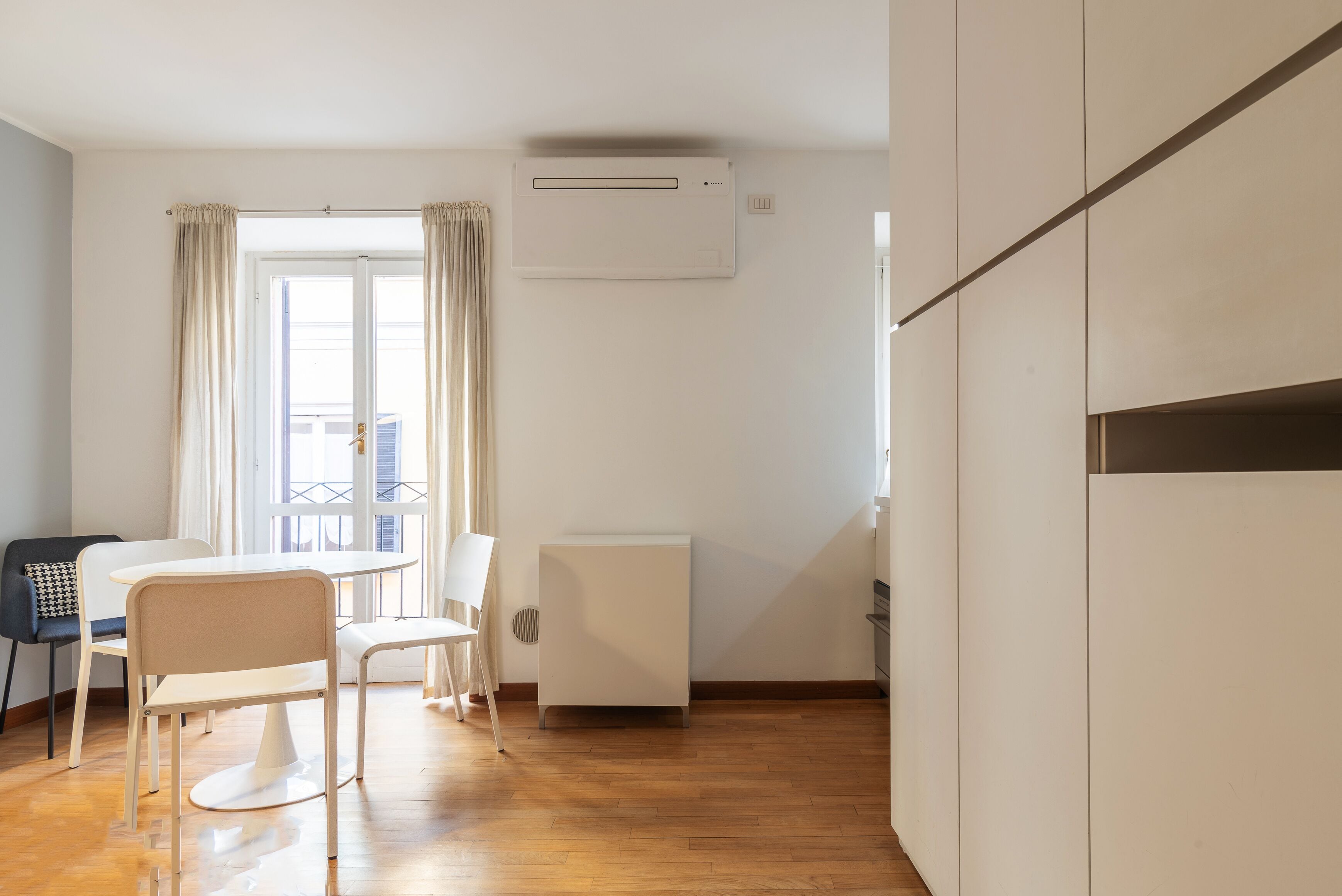 Quarto moderno e minimalista com área de refeições, radiador e janela com cortinas.