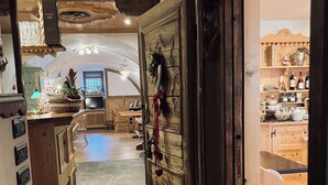 A rustic interior with a stone floor, wooden furniture, and a large wooden door with decorations. - HOTEL SALVANEL BOSCHETTO ROLAND DI DAPRA’ MARIA MADDALENA (Cavalese)