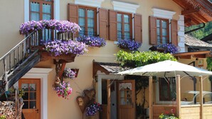 A traditional chalet with wooden shutters, a wooden staircase, and flower boxes on the exterior walls. - HOTEL SALVANEL BOSCHETTO ROLAND DI DAPRA’ MARIA MADDALENA (Cavalese)