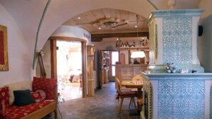 A cozy interior with a wooden bench, a patterned column, and a stone floor. - HOTEL SALVANEL BOSCHETTO ROLAND DI DAPRA’ MARIA MADDALENA (Cavalese)