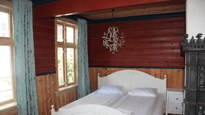 A room with a wooden paneled wall, a white bed with a headboard, a small bedside table, and a dark wooden cabinet. - Center Villa (Bergen)
