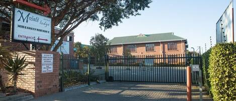 A gated entrance to a building with a sign indicating "Mosate lodge" and directions for bus entrance and delinquencies in Dorp Street.