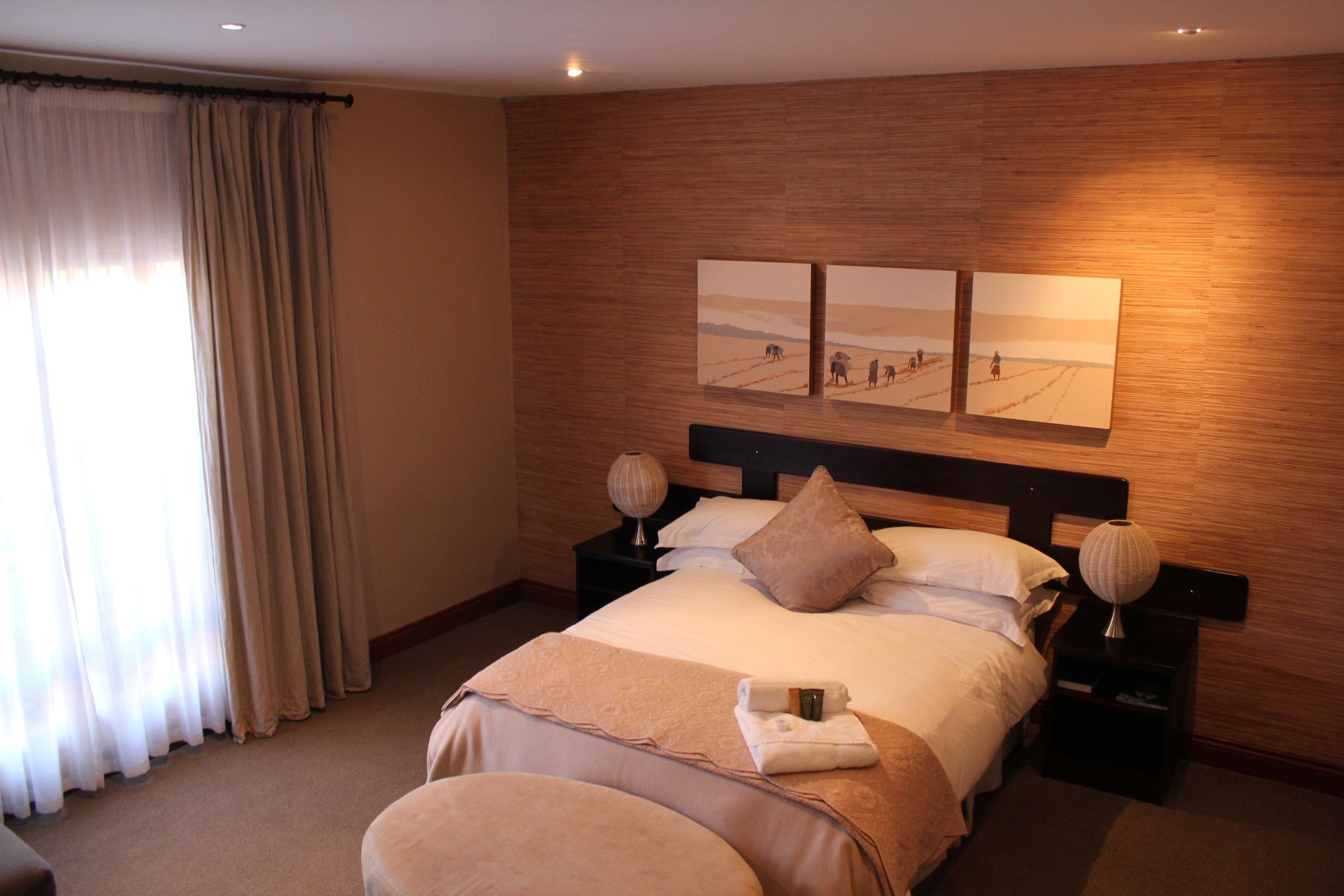 A hotel room with a large bed, two bedside tables, a headboard, and artwork on the wall.
