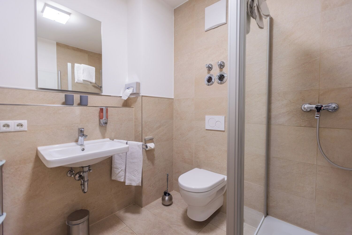 Uma casa de banho moderna com lavatório, sanita e chuveiro.