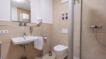 Uma casa de banho moderna com lavatório, sanita e chuveiro.