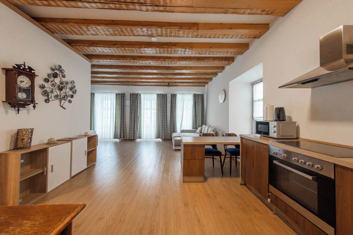 A spacious kitchen with wooden cabinets, a dining area, and a living room with a sofa.