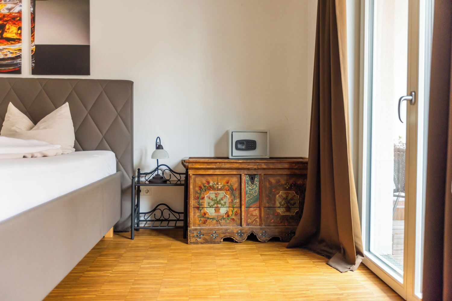 A bedroom with a bed, a nightstand, a lamp, a radio, and a wooden cabinet.