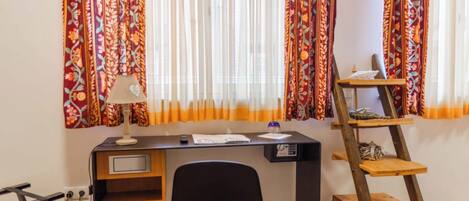A room with a desk, chair, and a wooden ladder shelf.