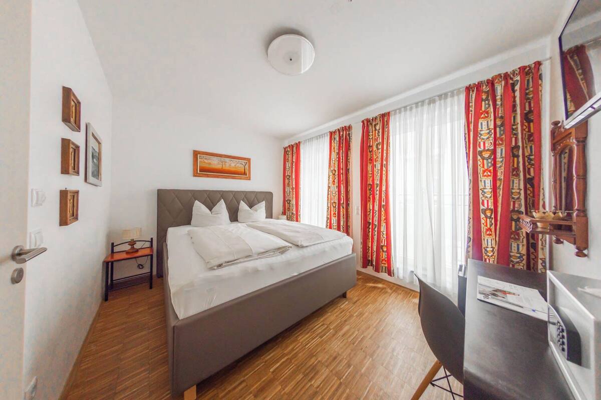 A modern hotel room with a large bed, a desk, and a television.