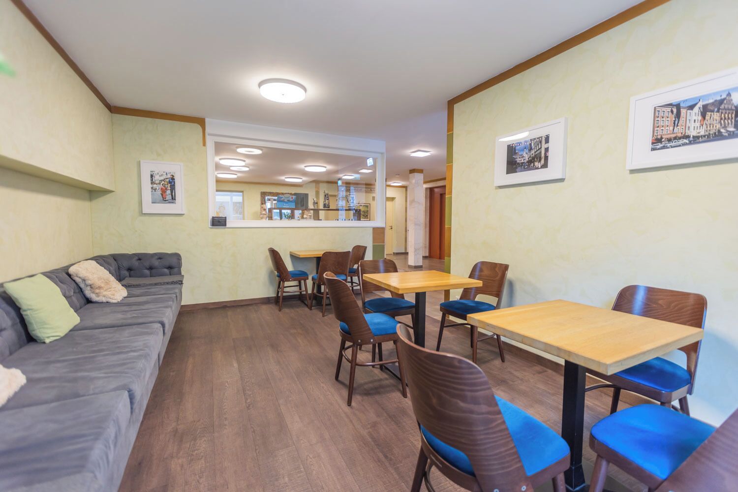 A hotel room with a sofa, dining table, chairs, and a mirror.