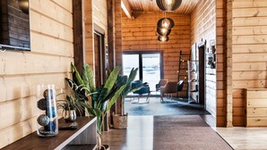 A wooden interior with a long hallway, a central plant, and a view to the outside. - Lighthouse Inn (Suðurnesjabær)