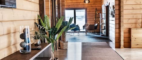 A wooden interior with a long hallway, a central plant, and a view to the outside.