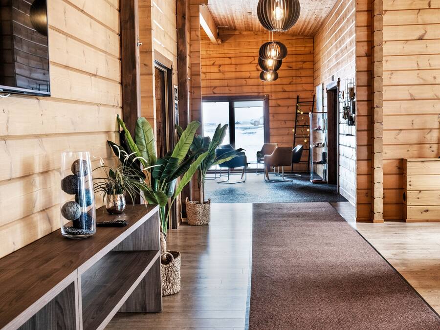 A wooden interior with a long hallway, a central plant, and a view to the outside.