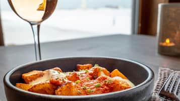 A bowl of food on a table with a glass of white wine and a candle in the background.