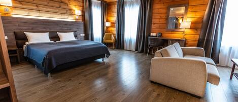 Una habitación con paneles de madera, una cama, un sofá, un escritorio y una silla.
