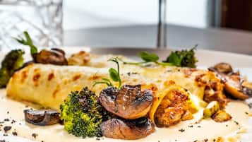 Une assiette de nourriture comprenant des champignons, des brocolis et un verre de vin rouge.