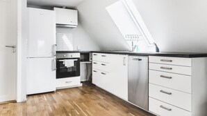 A modern kitchen with white cabinets, a black countertop, and a stainless steel dishwasher. - Skuteviken Apartments (Bergen)