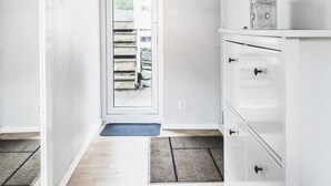 A hallway with a wooden floor, white walls, a white cabinet with drawers, a door leading outside, and a framed picture on the wall. - Skuteviken Apartments (Bergen)