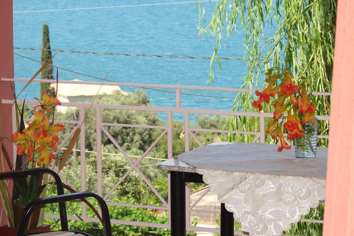 A balcony with a table and chairs, overlooking a body of water.