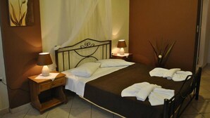 A neatly made bed with white linens, two bedside lamps, and a bedside table with a lamp. - Christianna Studios (Lefkada)