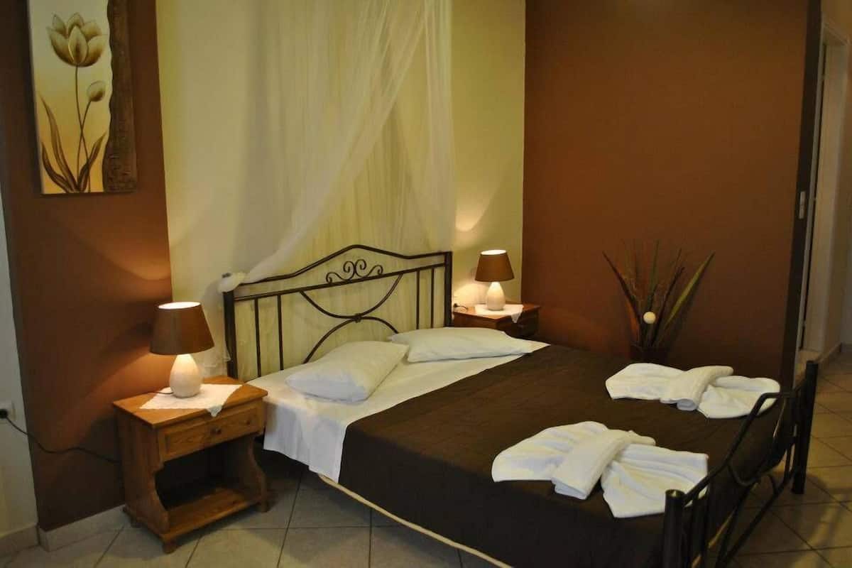 A neatly made bed with white linens, two bedside lamps, and a bedside table with a lamp.