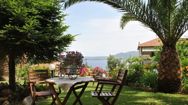 A garden with a table and chairs, a bicycle, and a view of the sea. - Christianna Studios (Lefkada)
