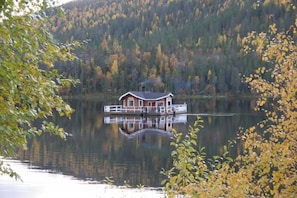 A houseboat on a calm lake surrounded by autumn foliage. - Immelkartano (Kittila)