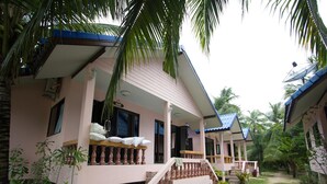 A pink bungalow with a covered porch, a staircase, and a small garden area. - Chaiwat Resort (Laem Sing)