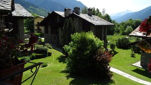 A traditional stone building with a sloped roof, surrounded by well-maintained gardens and a mountainous backdrop. - La Rouine - Morgex (Morgex)