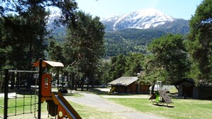 A playground with a slide and climbing structure, surrounded by trees and a mountain in the background. - La Rouine - Morgex (Morgex)