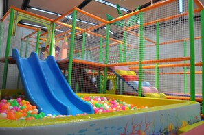 Un área de juegos interior con un tobogán y una piscina de pelotas.