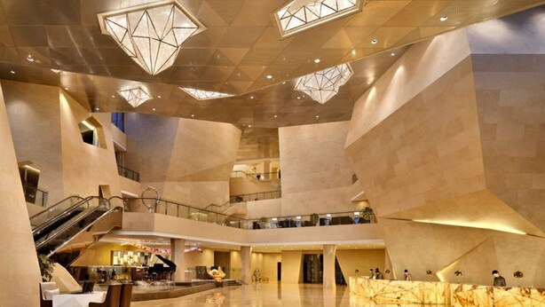 A spacious atrium with a grand staircase, multiple levels, and a central seating area with a piano. - CITIC Jinling Hotel (Pinggu)