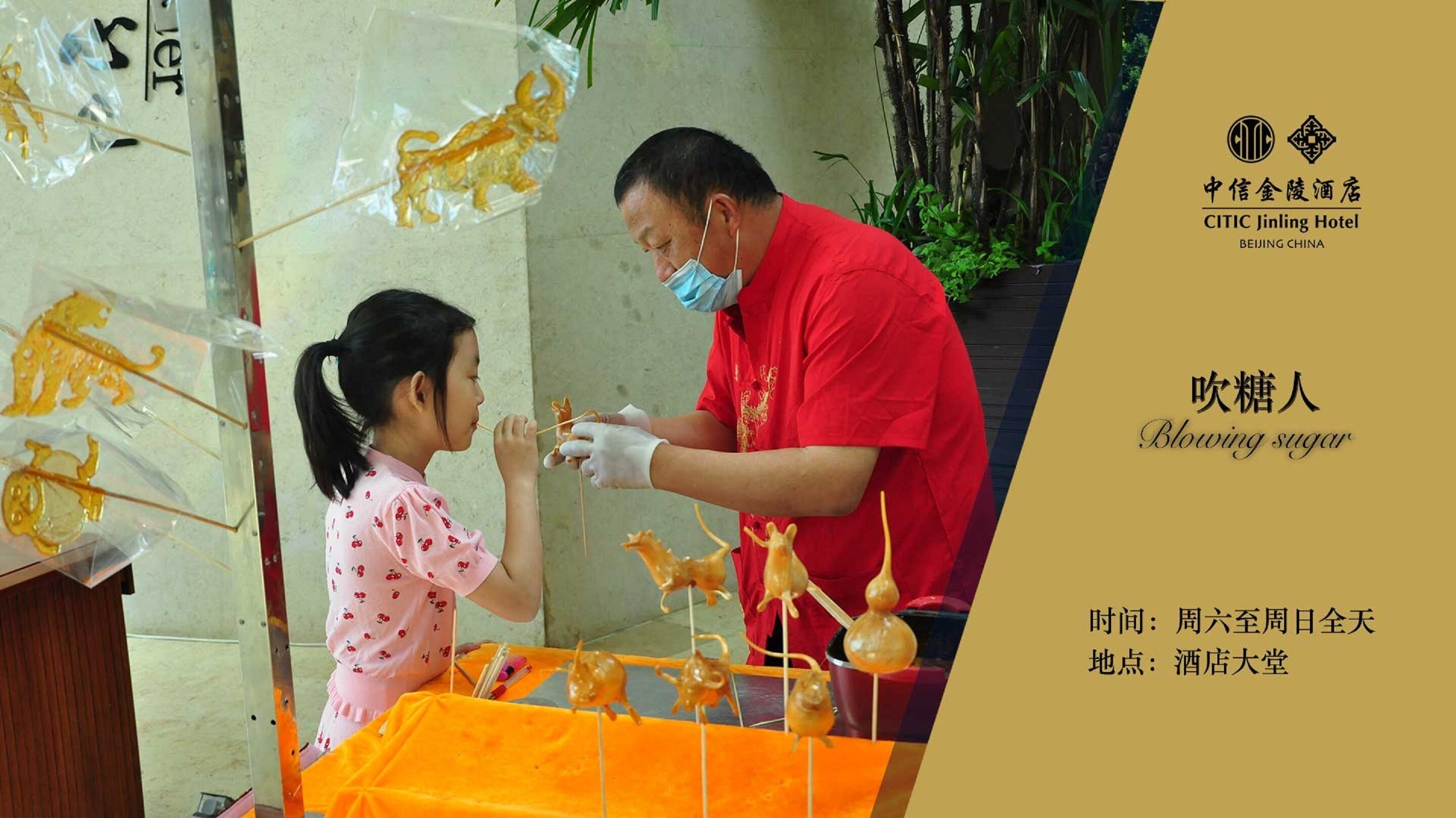 A man and a child at a table with sugar sculptures, a sign for CITIC Jinling Hotel, and a golden lion decoration.
