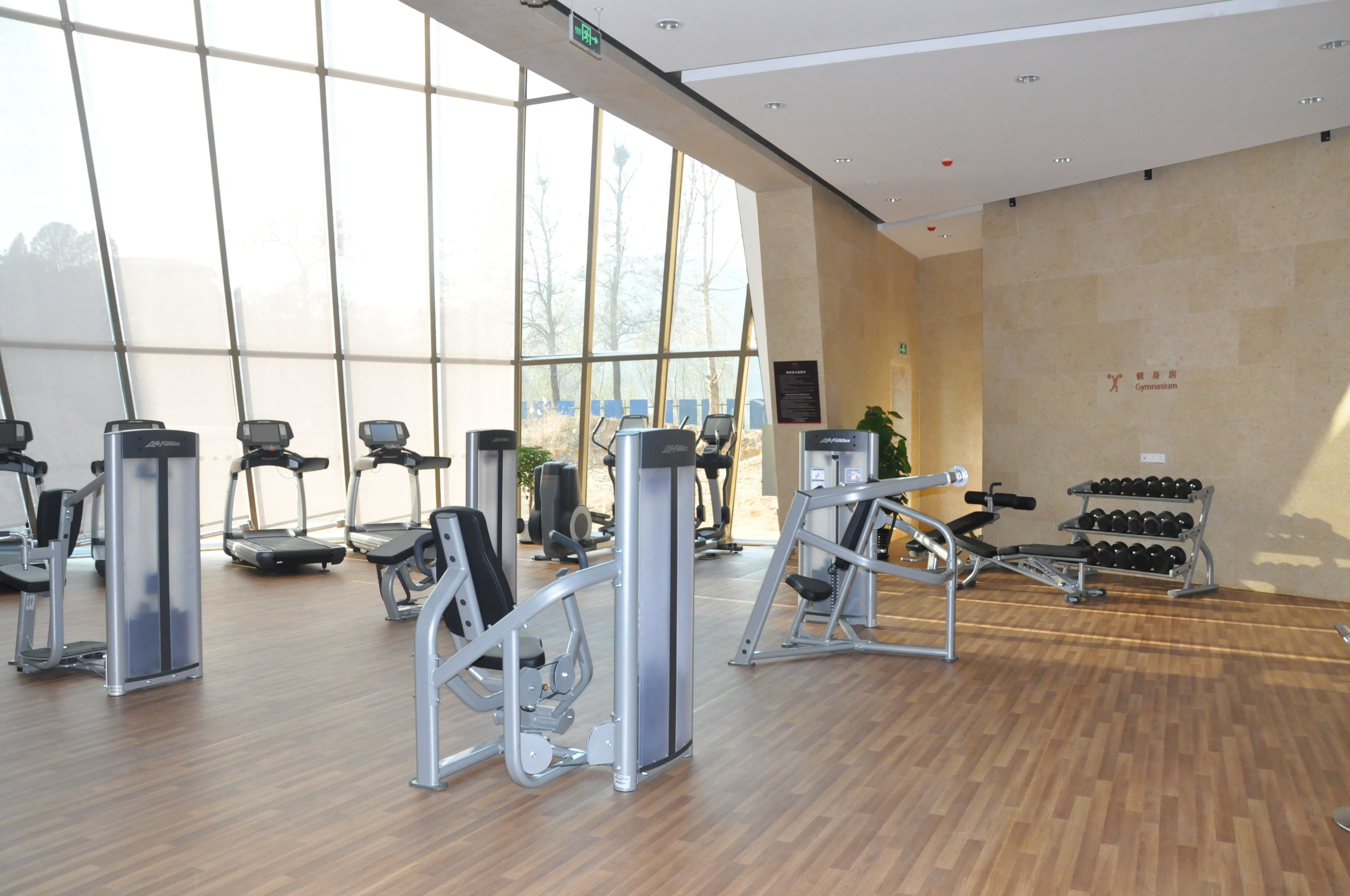 A gym with cardio machines, weightlifting equipment, and dumbbells.