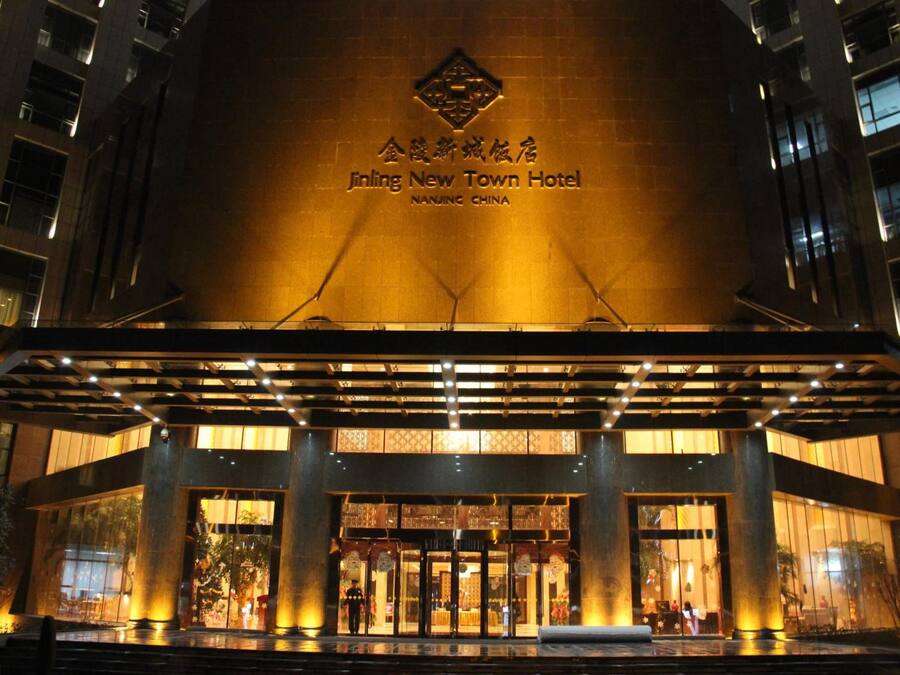 The exterior of the Jinling New Town Hotel with illuminated signage and a covered entrance.