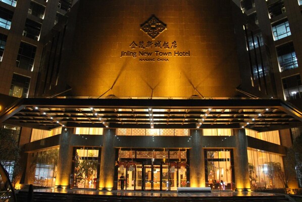 The exterior of the Jinling New Town Hotel with illuminated signage and a covered entrance.