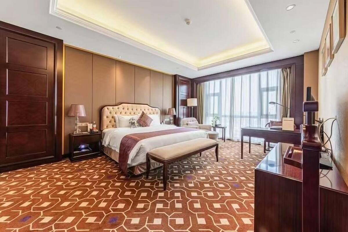 A hotel room with a large bed, a desk, and a view of the city.