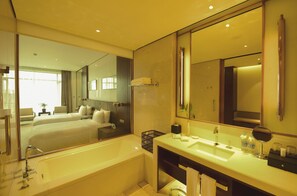 Un baño de hotel moderno con un espejo grande, una bañera, un lavabo y una ducha.