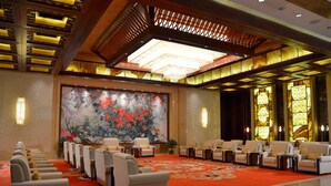A hotel lobby with a red carpet, rows of seating, a large floral painting, and traditional lighting fixtures. - Jinling Yew Resort Wuxi (Wuxi)