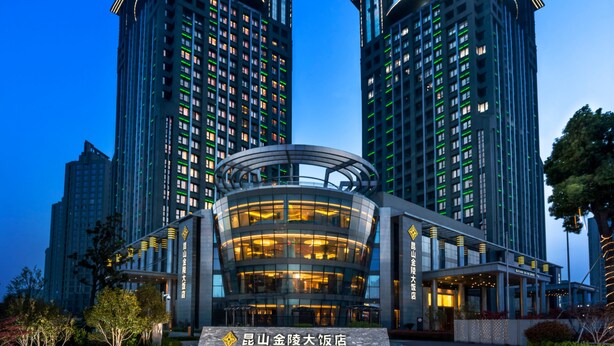 Um hotel moderno com entrada marcante e dois edifícios altos ao fundo.
