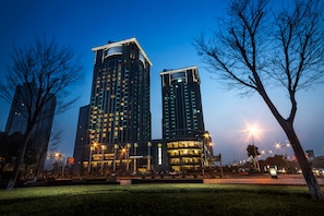 Two high-rise buildings with illuminated windows and a well-maintained lawn in the foreground.