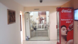 A hallway with a Coca-Cola vending machine, a door labeled "RECEPTION," and a staircase leading to an upper floor. - Stellamares Apartamentos (Salvador)