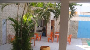 A covered patio area with outdoor seating, a large planter, and a stone wall. - Stellamares Apartamentos (Salvador)