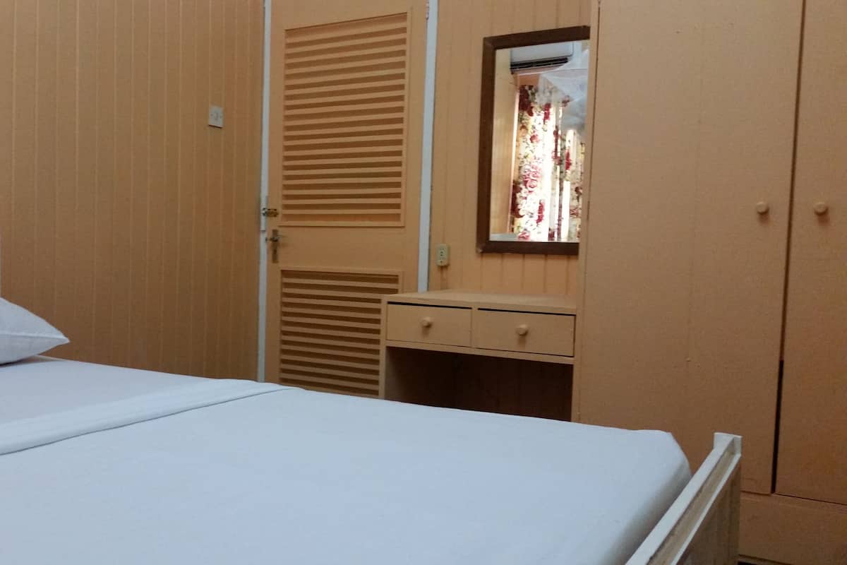 Ein Schlafzimmer mit Bett, Nachttisch, Spiegel und Kleiderschrank.