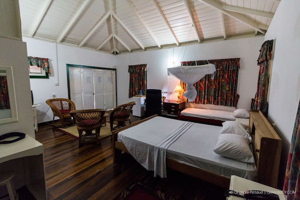A room with two beds, a chair, a desk, and a lamp.
