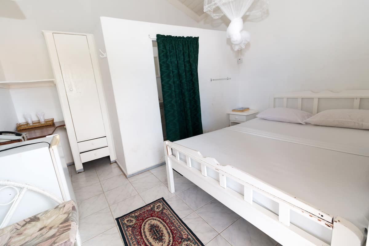 Ein Schlafzimmer mit einem weißen Bett, einem weißen Kleiderschrank, einem grünen Vorhang und einem weißen Nachttisch.