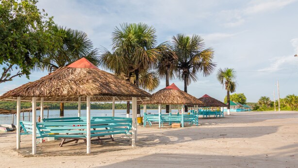 Ein Strand mit überdachten Pavillons und Bänken.