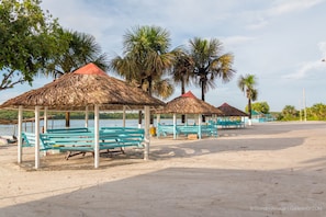 A beach with thatched-roof gazebos and benches. - Lake Mainstay Resort (Anna Regina)